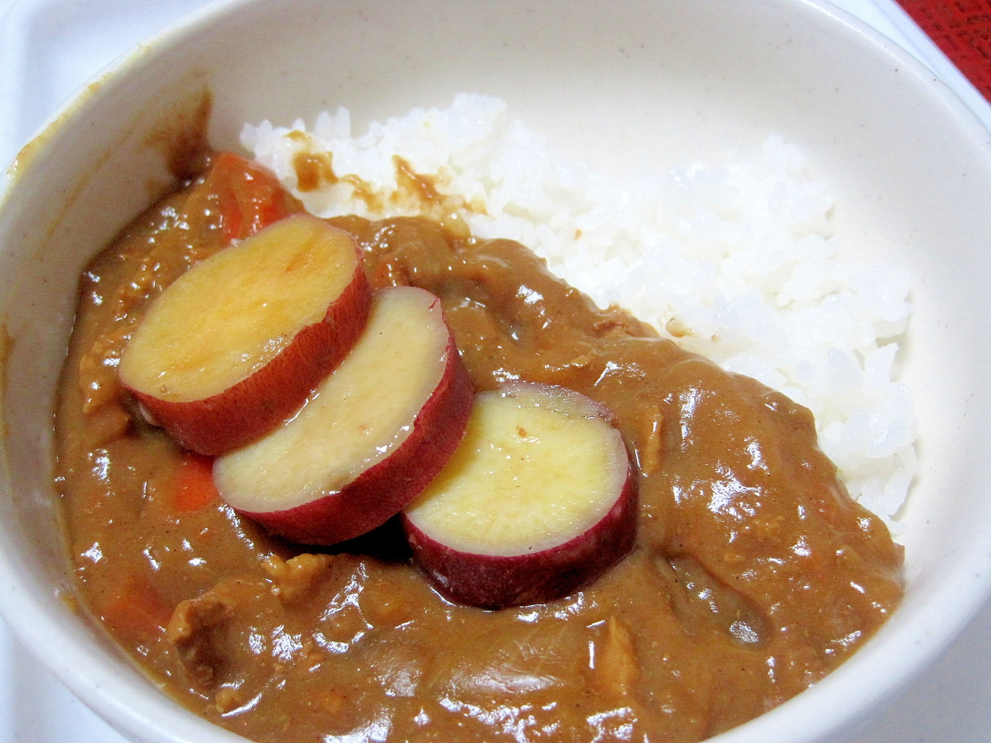 白い深皿に盛りつけられた豚肉とさつまいも、玉ねぎのカレー