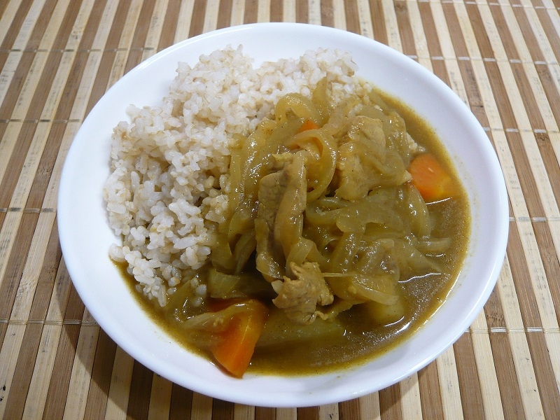 白い皿に入った豚肉と玉ねぎ、にんじんのカレーライス
