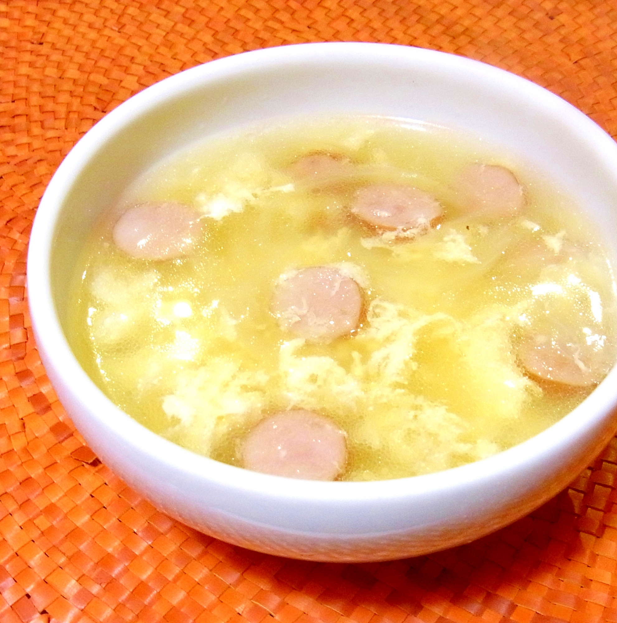 ウインナーと卵のスープが白い皿に盛り付けられているところ