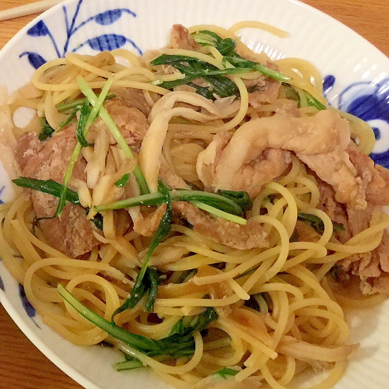 模様入りの白い皿に盛られた生姜焼きと水菜の和風パスタ