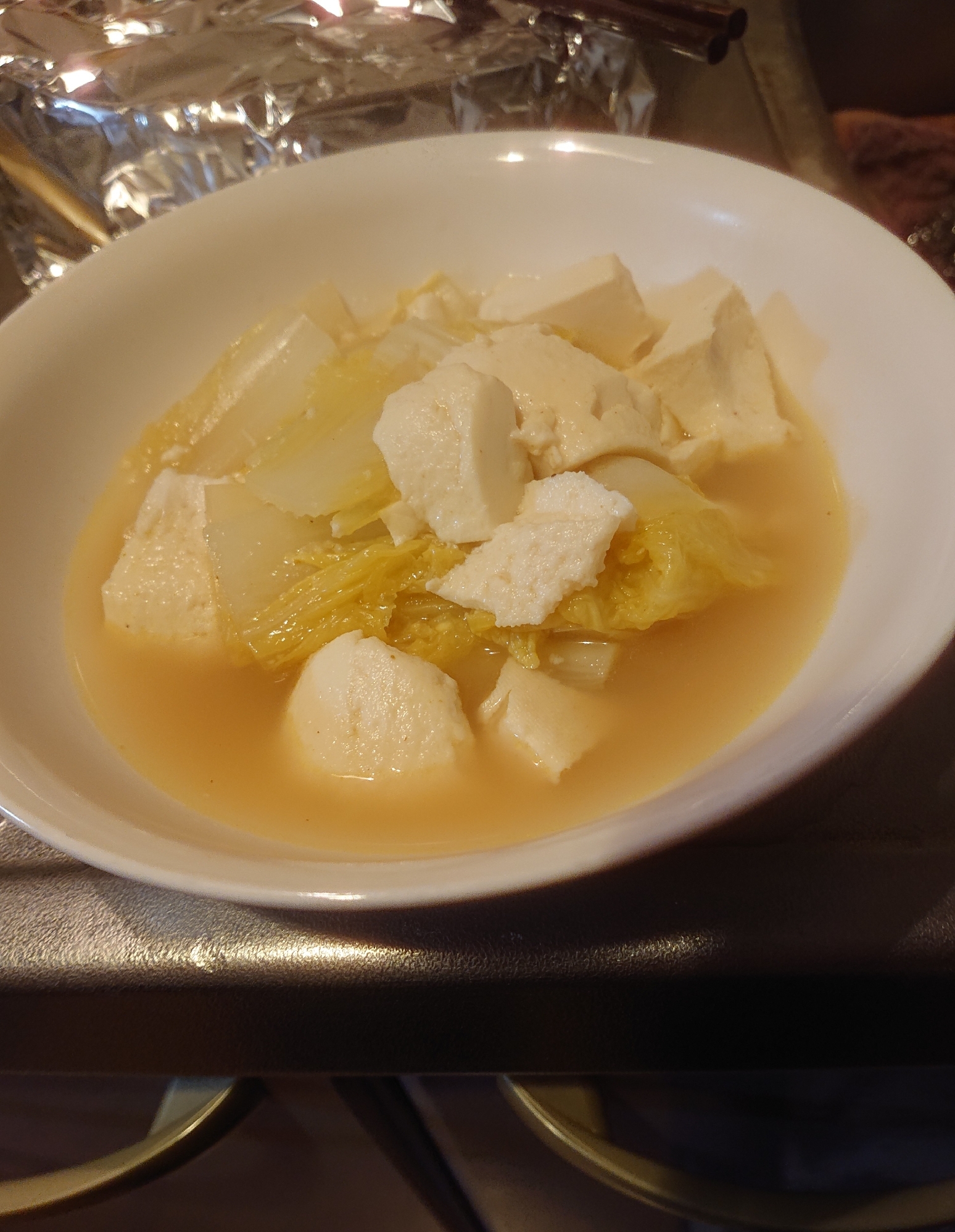 白い楕円型の器に入った白菜と豆腐のカレースープ