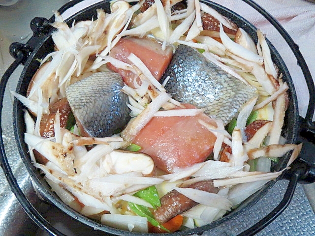 黒い鍋に入れられた塩鮭とごぼうの和風鍋