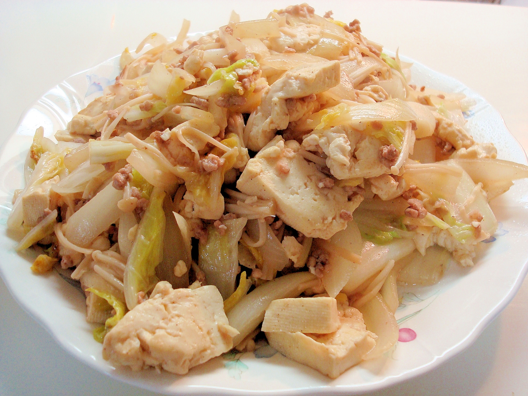白い皿に盛りつけられたくずし豆腐と豚ひき肉、野菜の炒め物