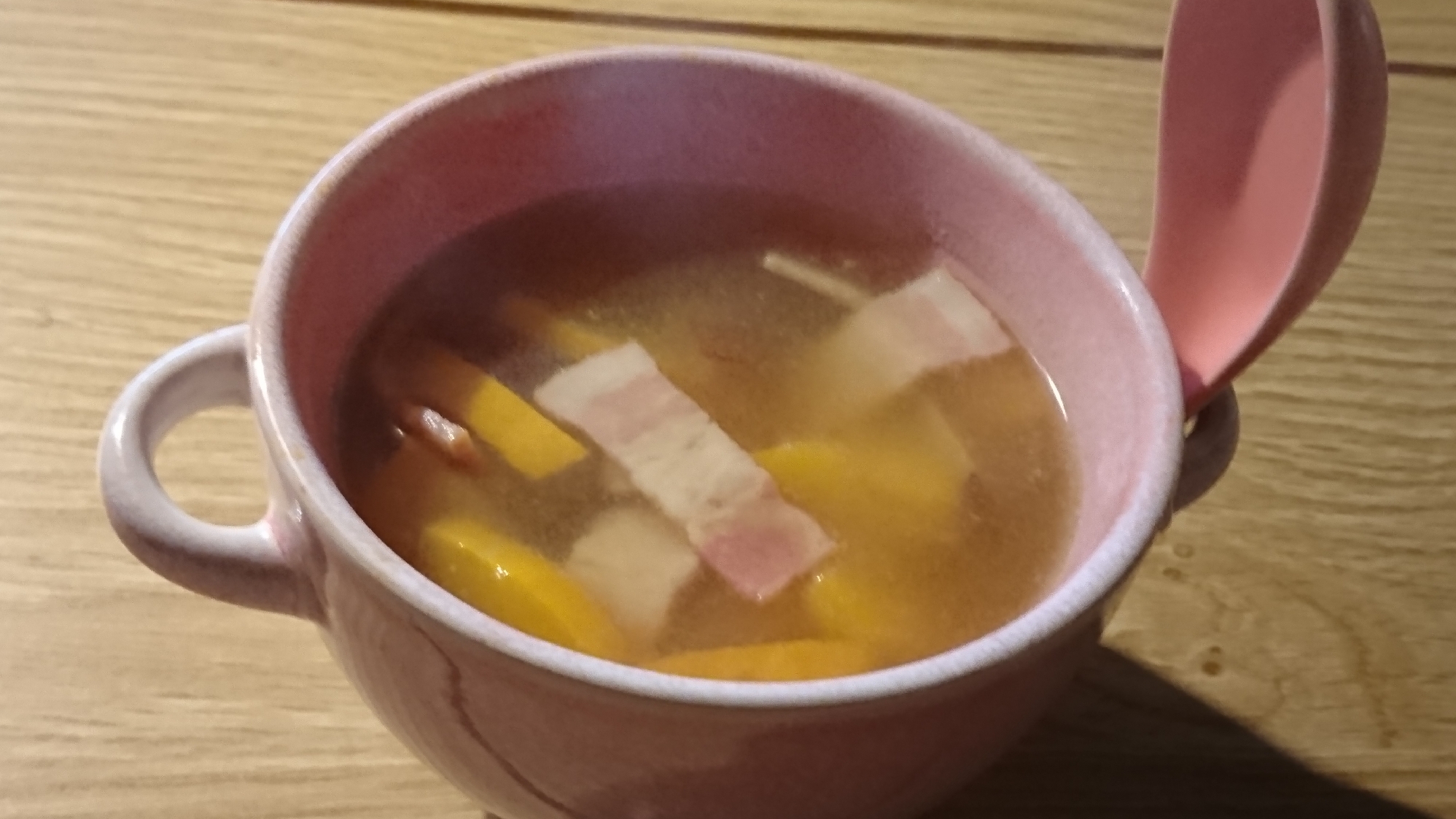 ピンクのスープカップによそったコリンキーとさつまいものコンソメスープ