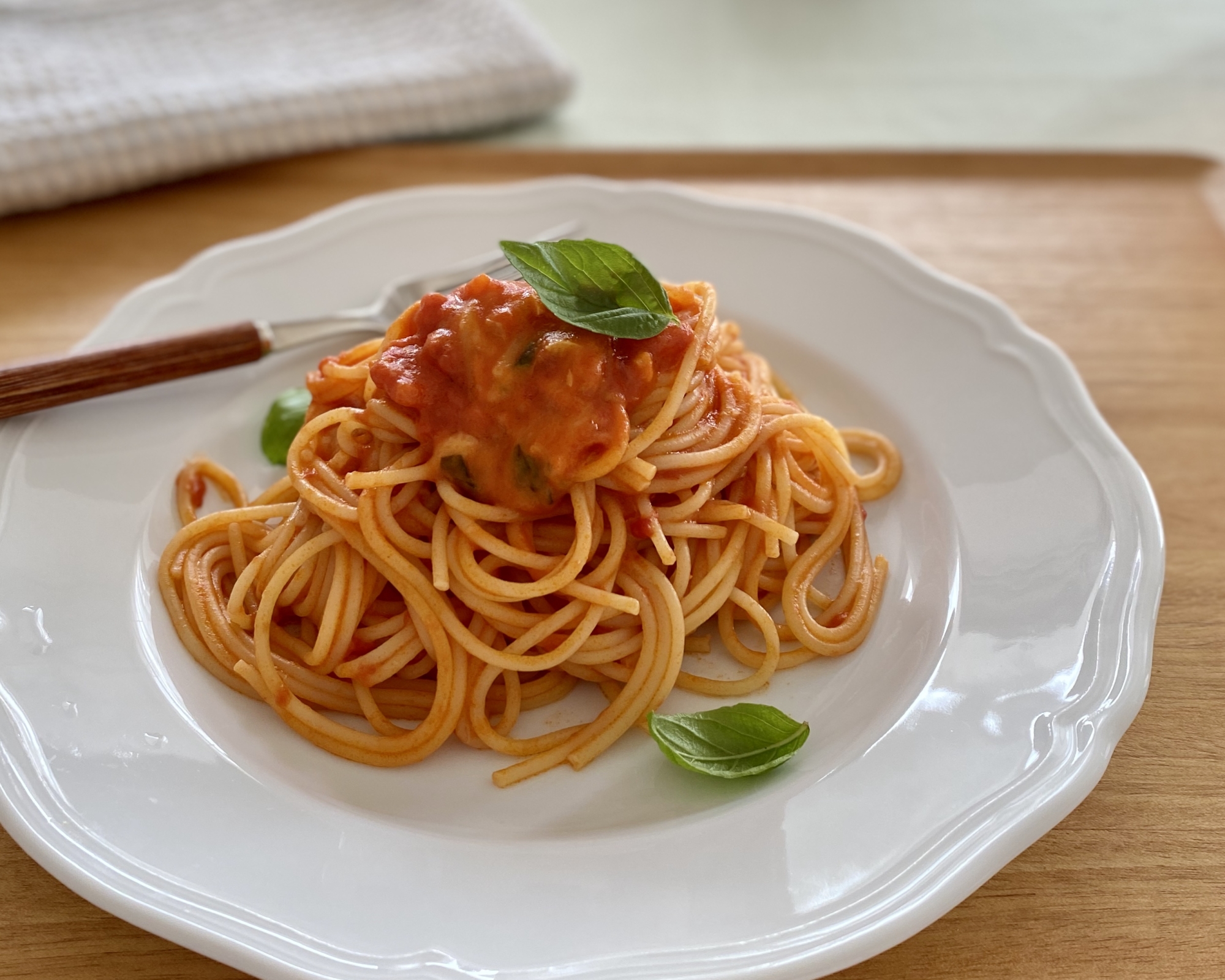 トマトとバジルのマルゲリータ風パスタが白い皿にのっている様子