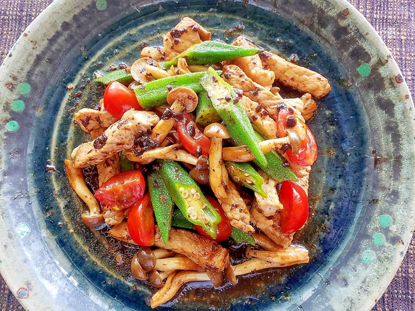 厚切りの豚ロースで作った豚ロース肉とオクラの豆鼓炒が青い皿に盛り付けられているところ