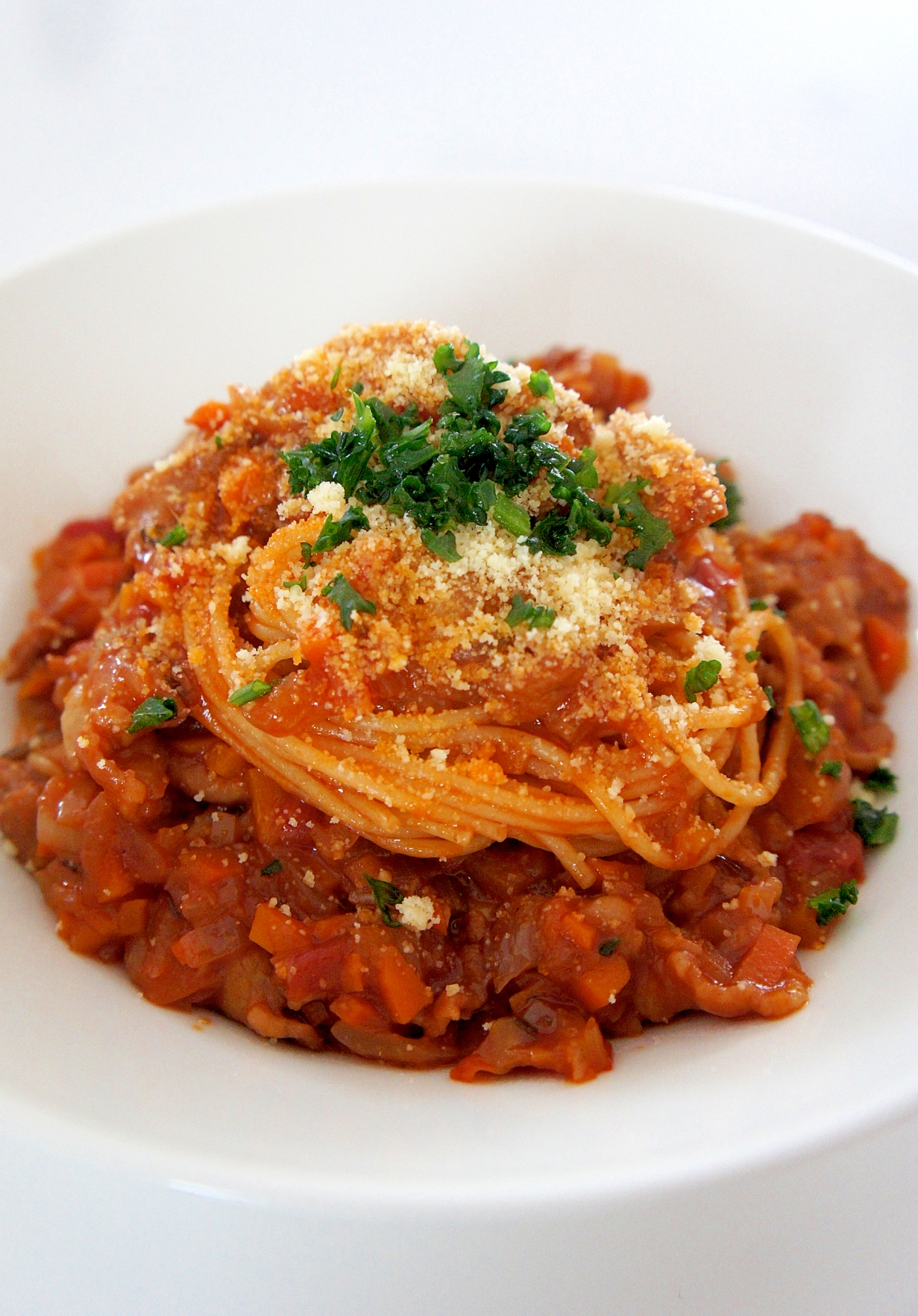 皿に盛り付けられた、豚バラ肉で作ったボロネーゼ風パスタ