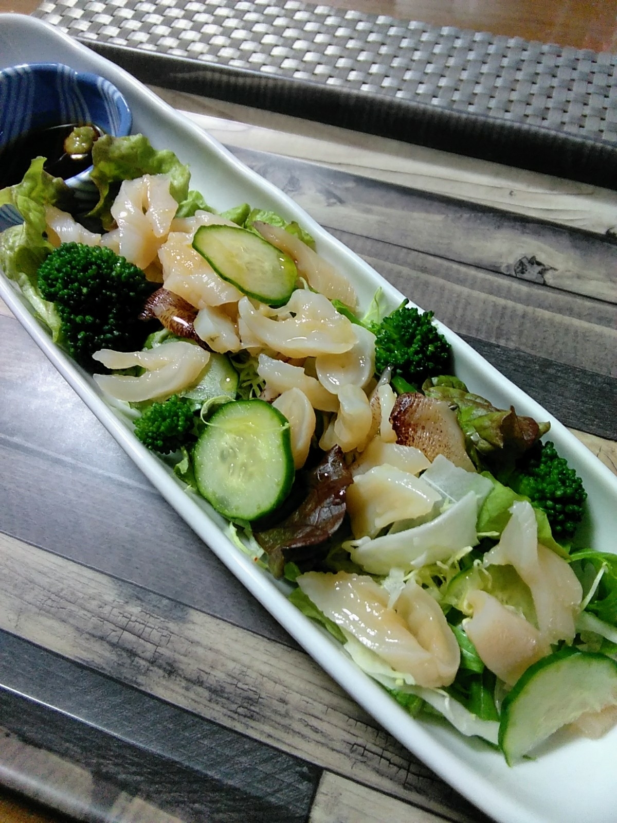 白く縦長の皿に盛り付けられたミル貝のグリーンサラダ