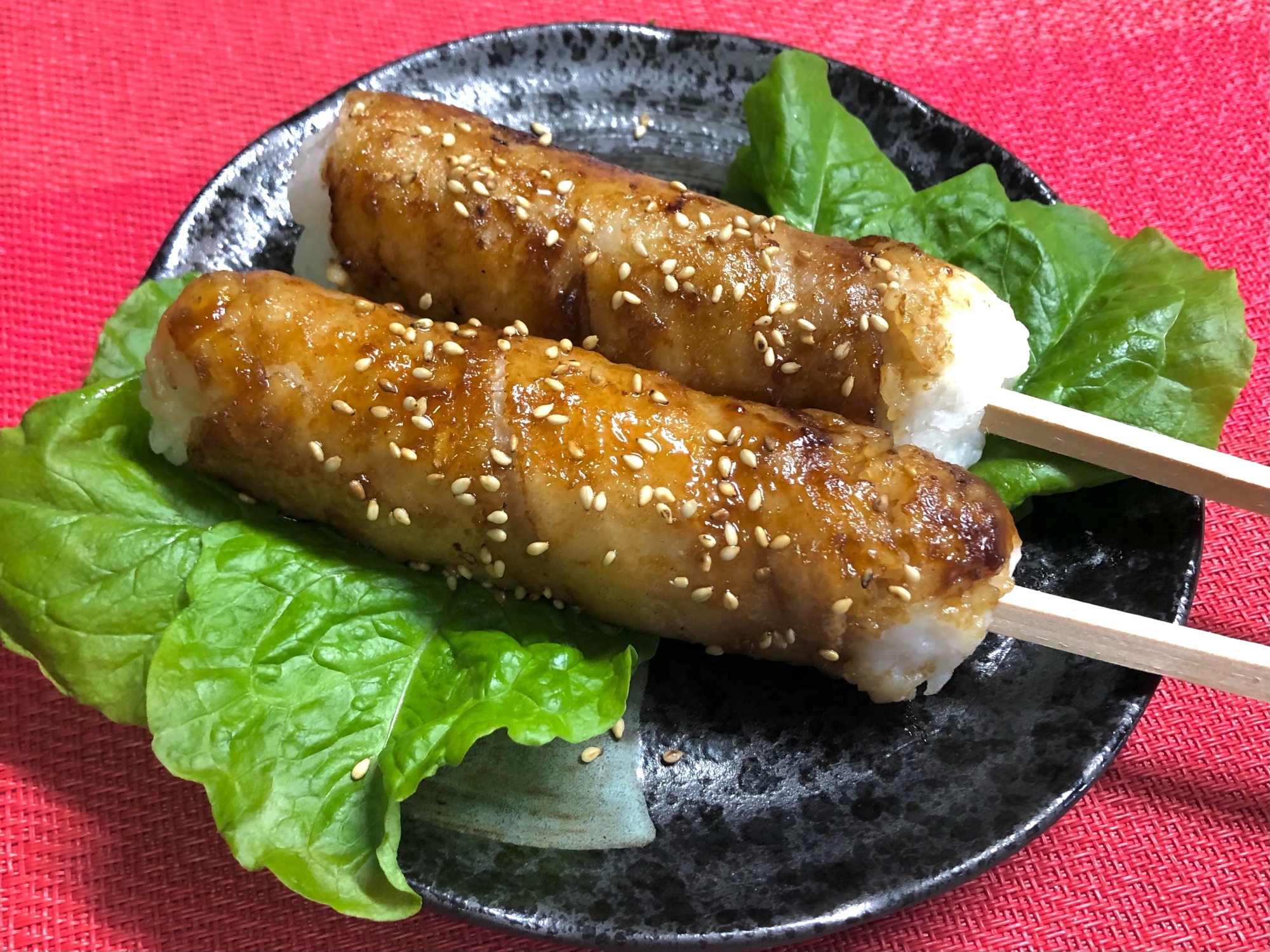 黒い皿の上に並べられた肉巻きスティックおにぎり