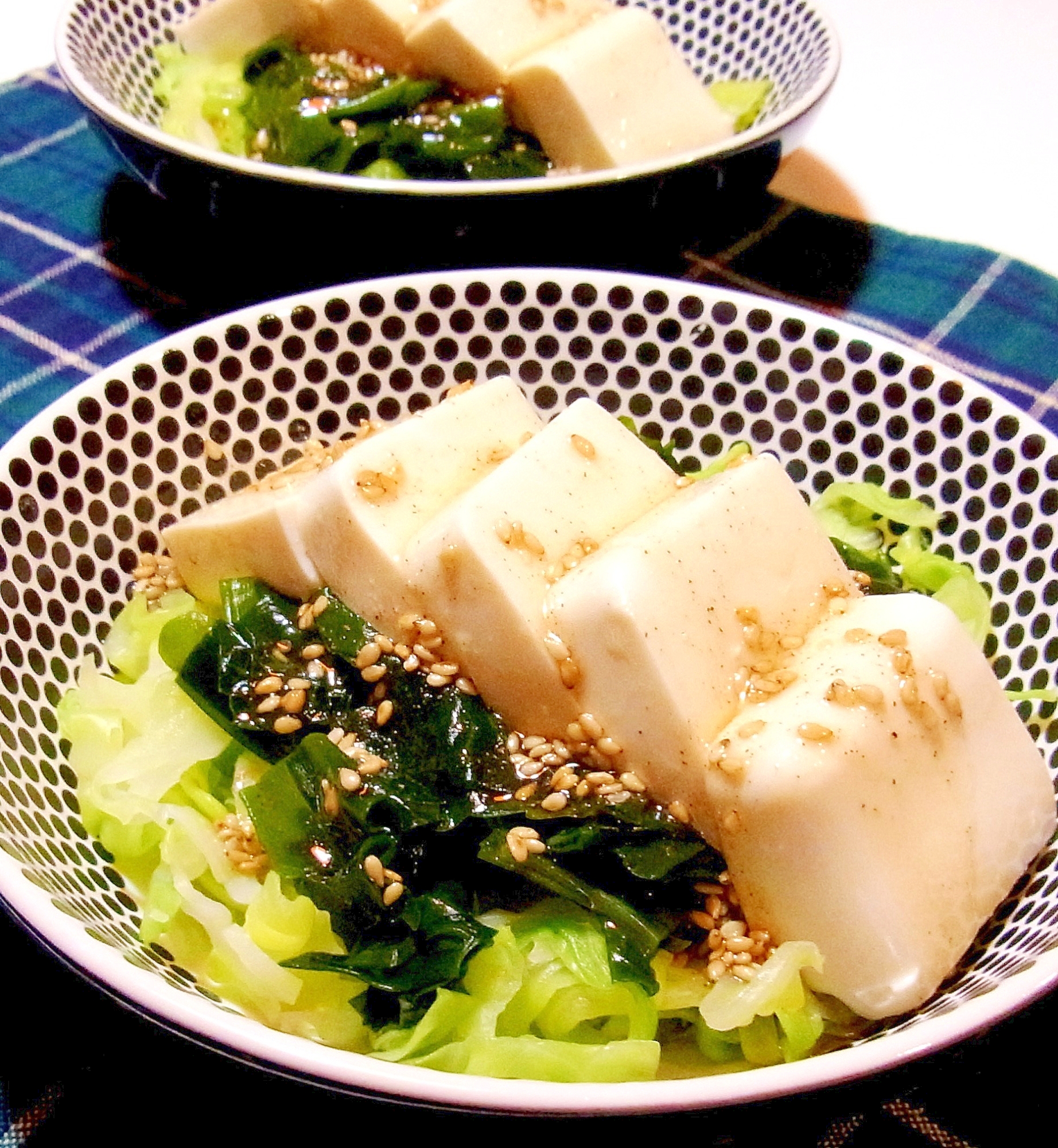 黒いドット柄の皿に盛られたキャベツと豆腐の中華サラダ