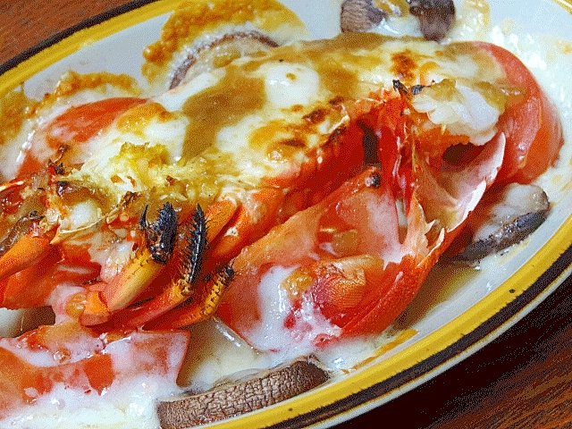 縁取りのある長皿に盛りつけられた伊勢海老とトマトのチーズ焼き