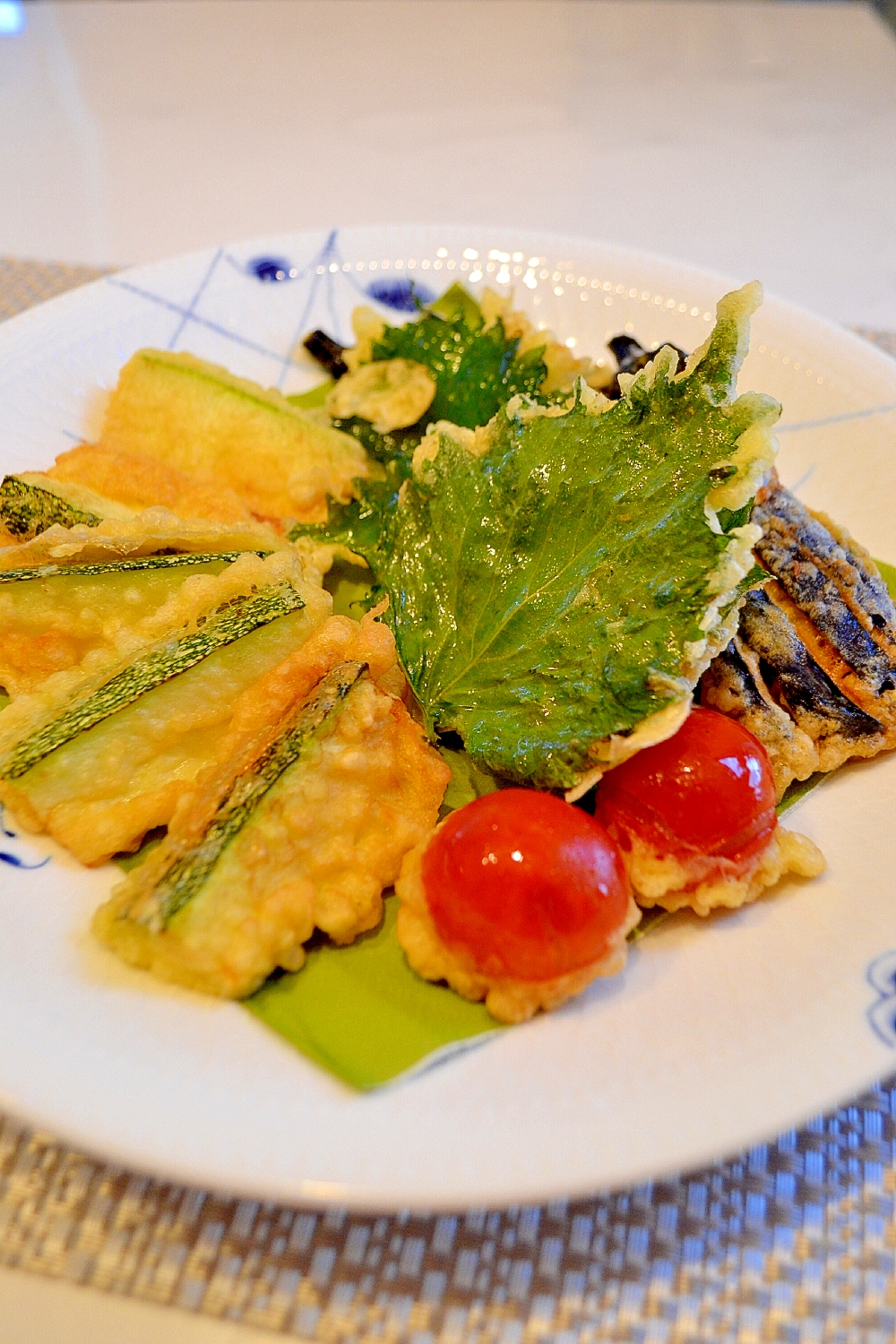 白い和の大皿に盛られた、ズッキーニとなすとミニトマトと大葉の天ぷら