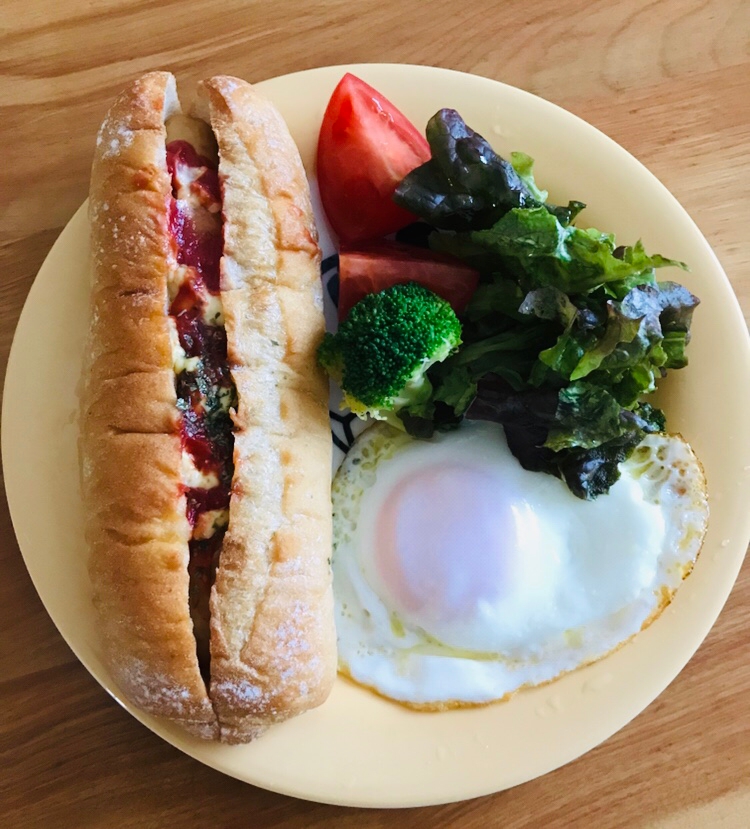 黄色いお皿に盛られたホットドッグと野菜と目玉焼き