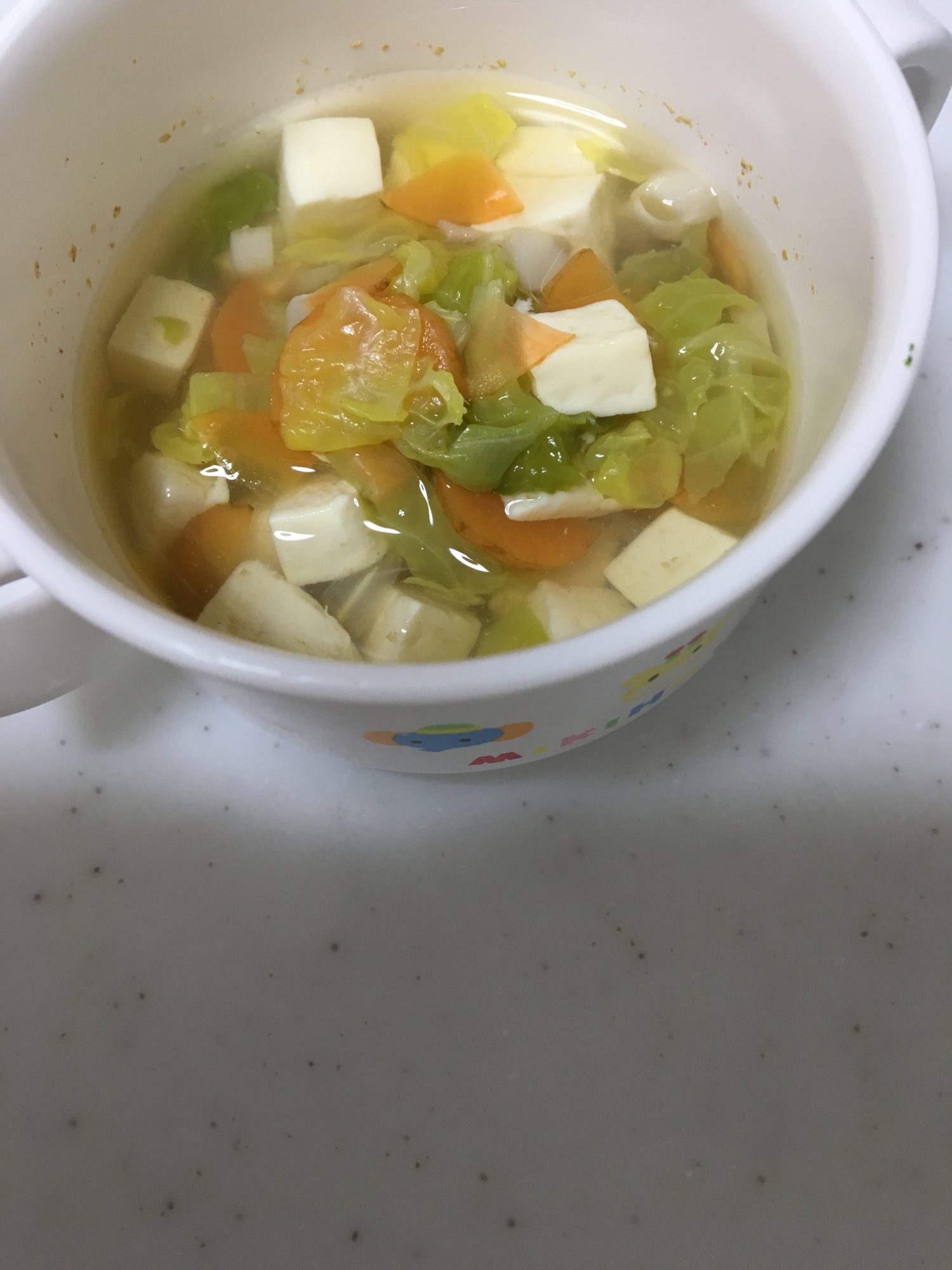 マグカップに具だくさんの白菜と豆腐の野菜スープが入っている