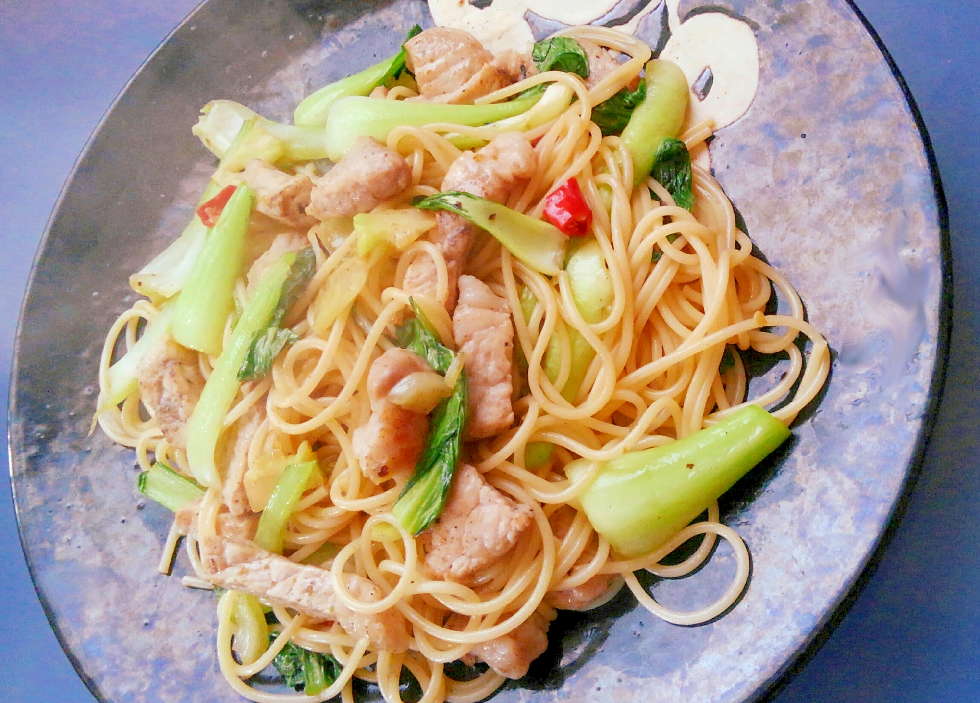 黒い皿にチンゲン菜と豚肉の和風パスタが盛られている様子