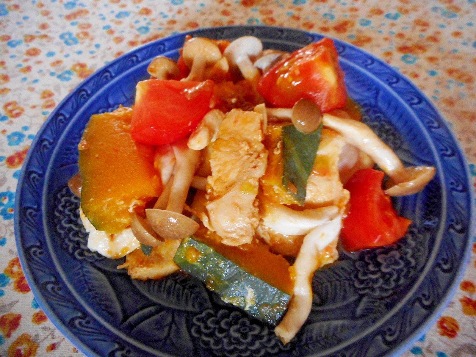 青い皿に盛られた、鶏むね肉とかぼちゃとトマトのしょうゆ炒め