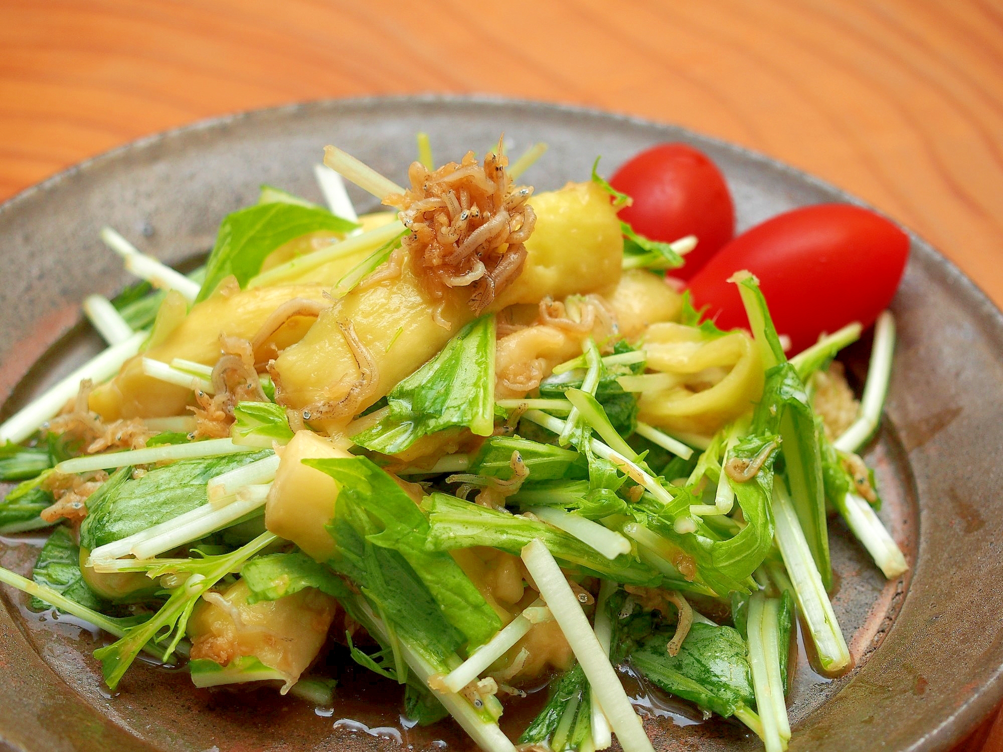 黒い丸皿に盛り付けた蒸しなすと水菜のカリカリじゃこサラダ