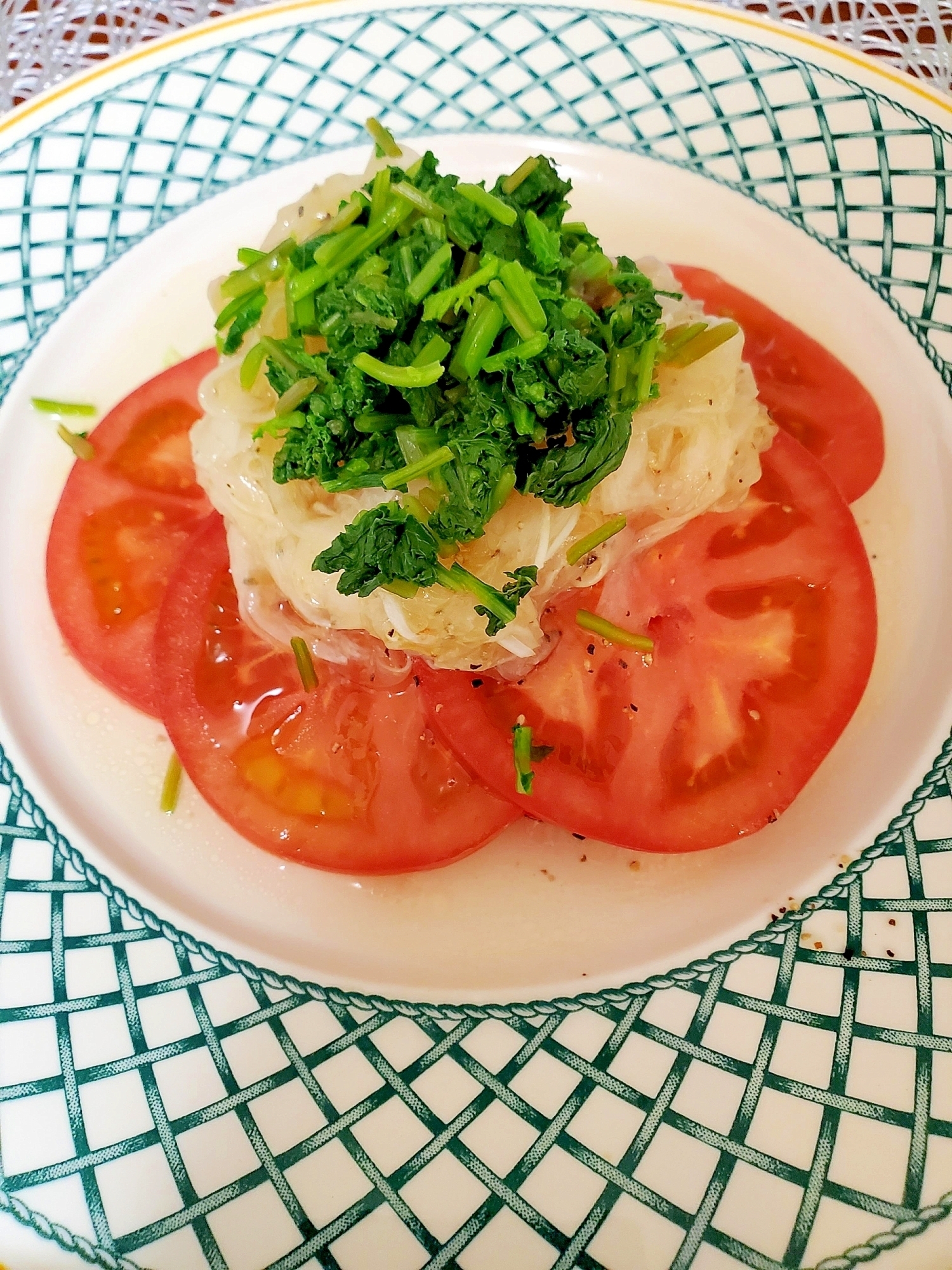 白い皿に盛り付けられているラディッシュの葉とトマトのサラダ