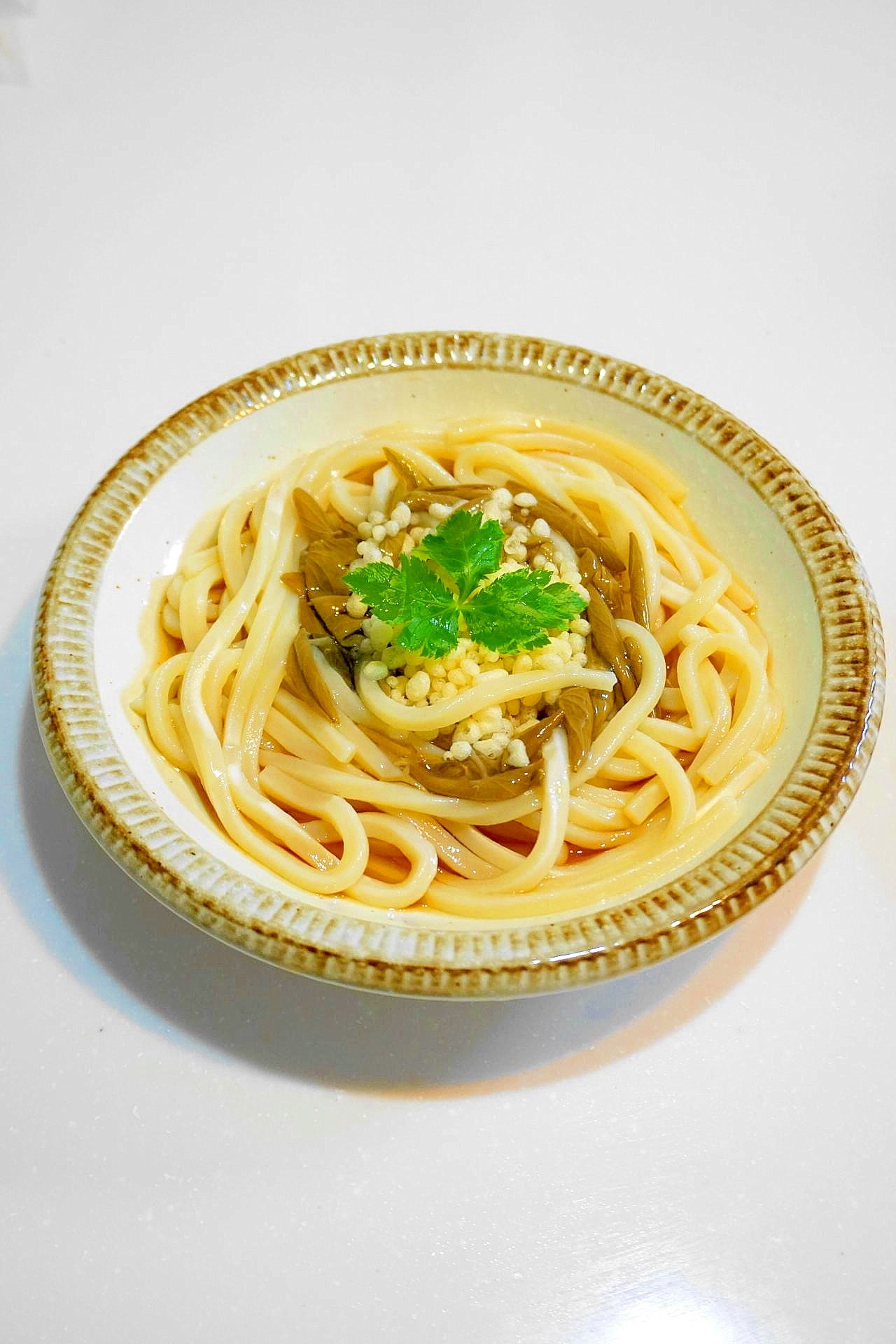 ベージュの縁の皿に盛られたじゅんさいと天かすの冷うどん