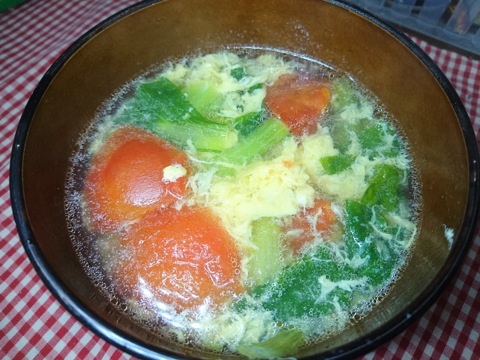 茶色い器に盛られた青菜とトマトの卵スープ