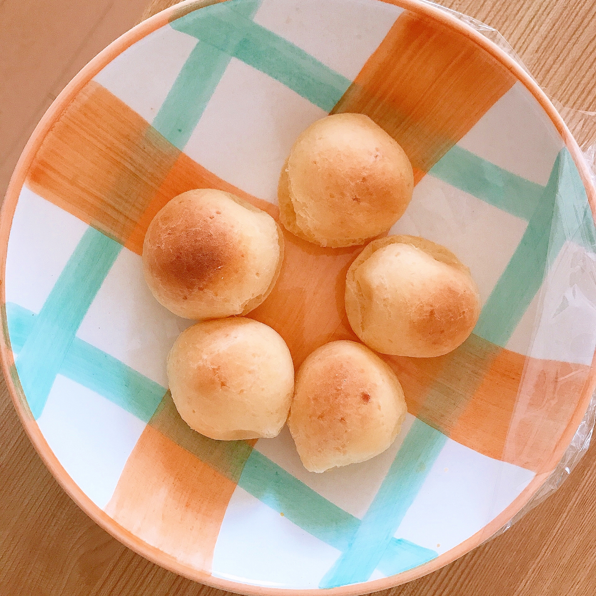 だんご粉を使った黄金色に焼き上がったもちもちのポンデケージョが、カラフルな平皿に並べられているところ