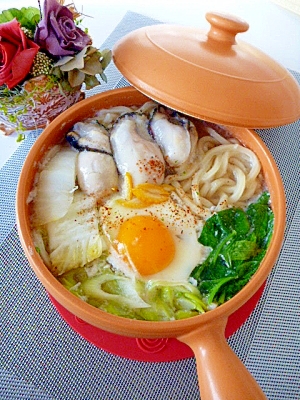 オレンジ色の取っ手付き鍋に盛り付けられた白菜の鍋焼きうどん