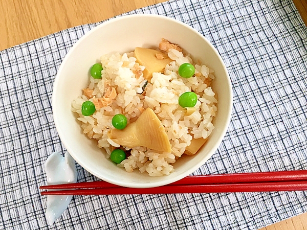 白色の茶碗に盛られたグリーンピースと鮭缶のたけのこご飯