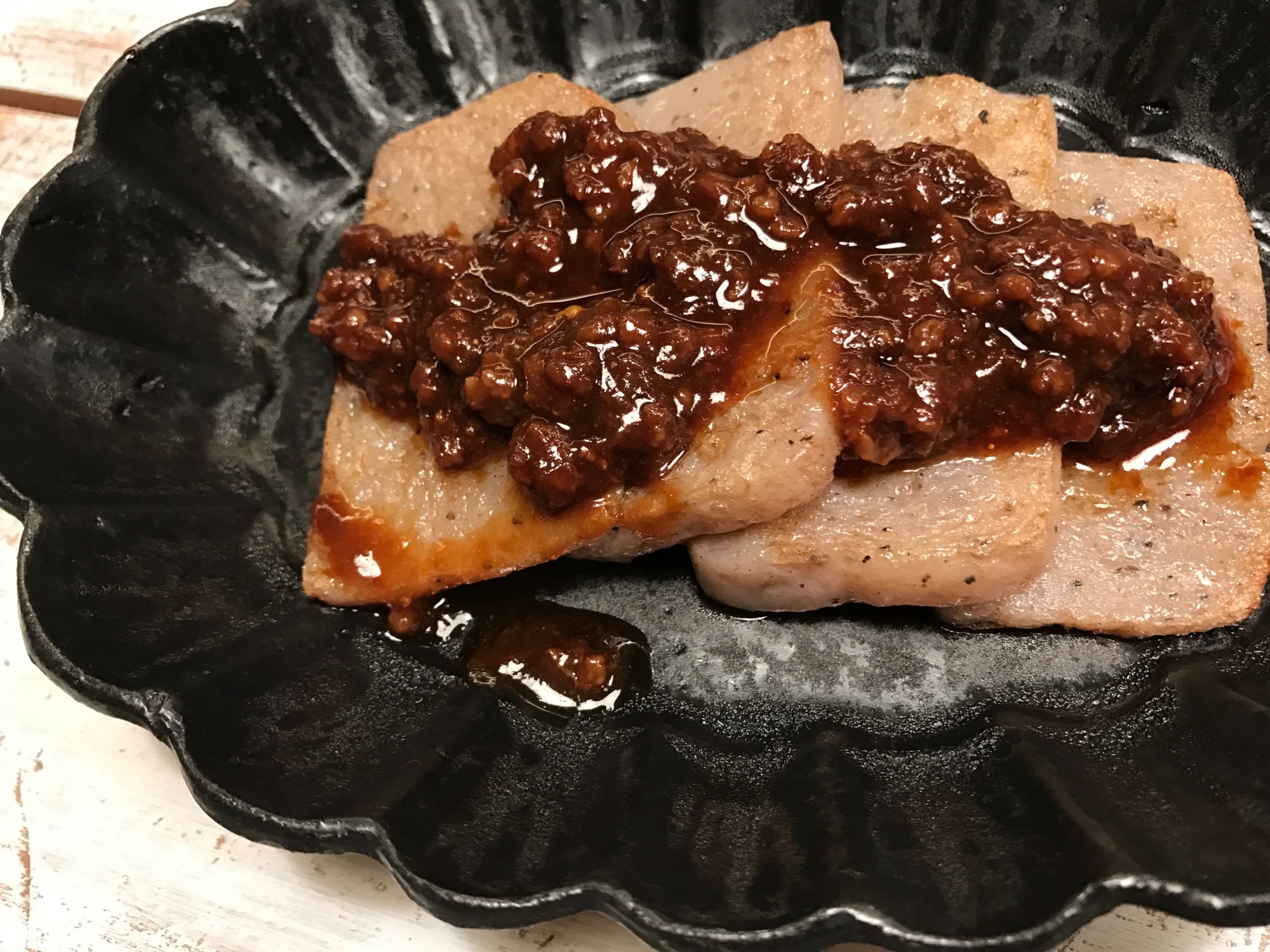 黒い皿に盛られた肉味噌のこんにゃく田楽