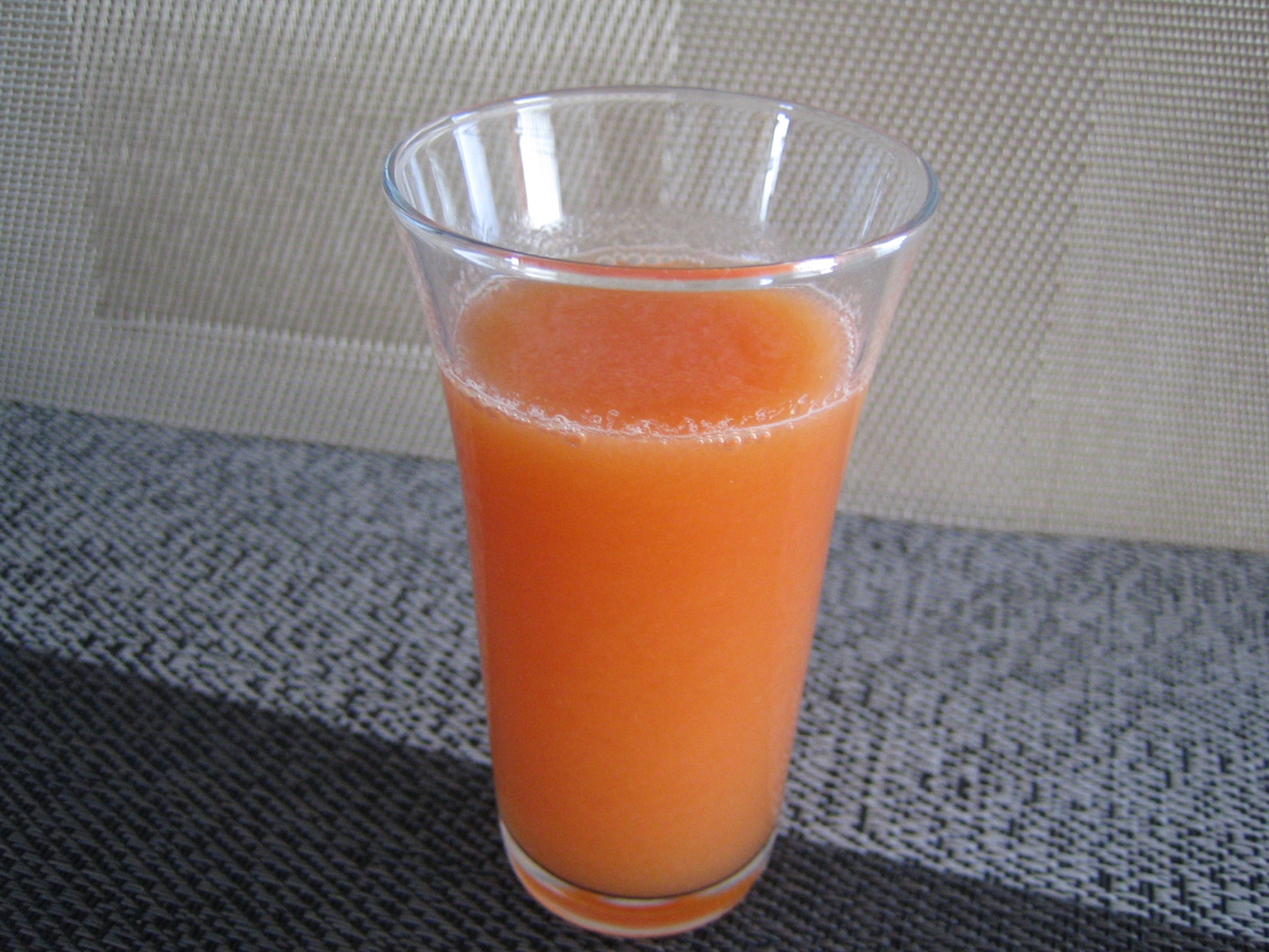 透明なグラスに入っている、オレンジ色のコールドプレスジュース