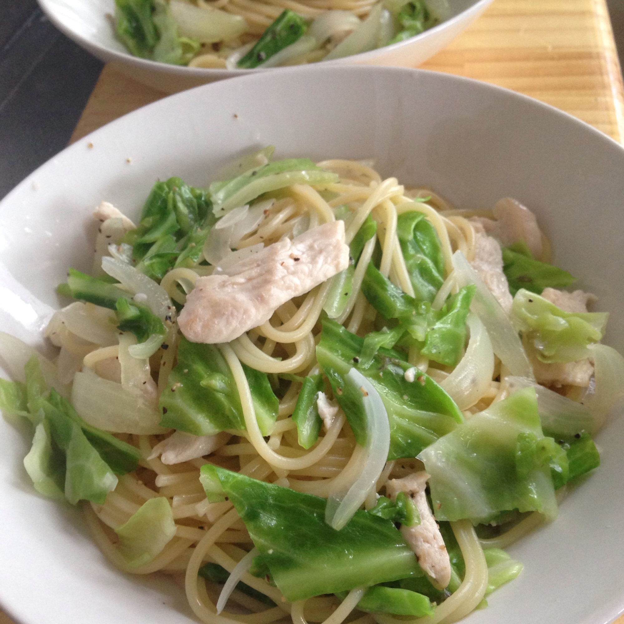 白い皿に盛り付けられている鶏胸肉とキャベツの白だしパスタ