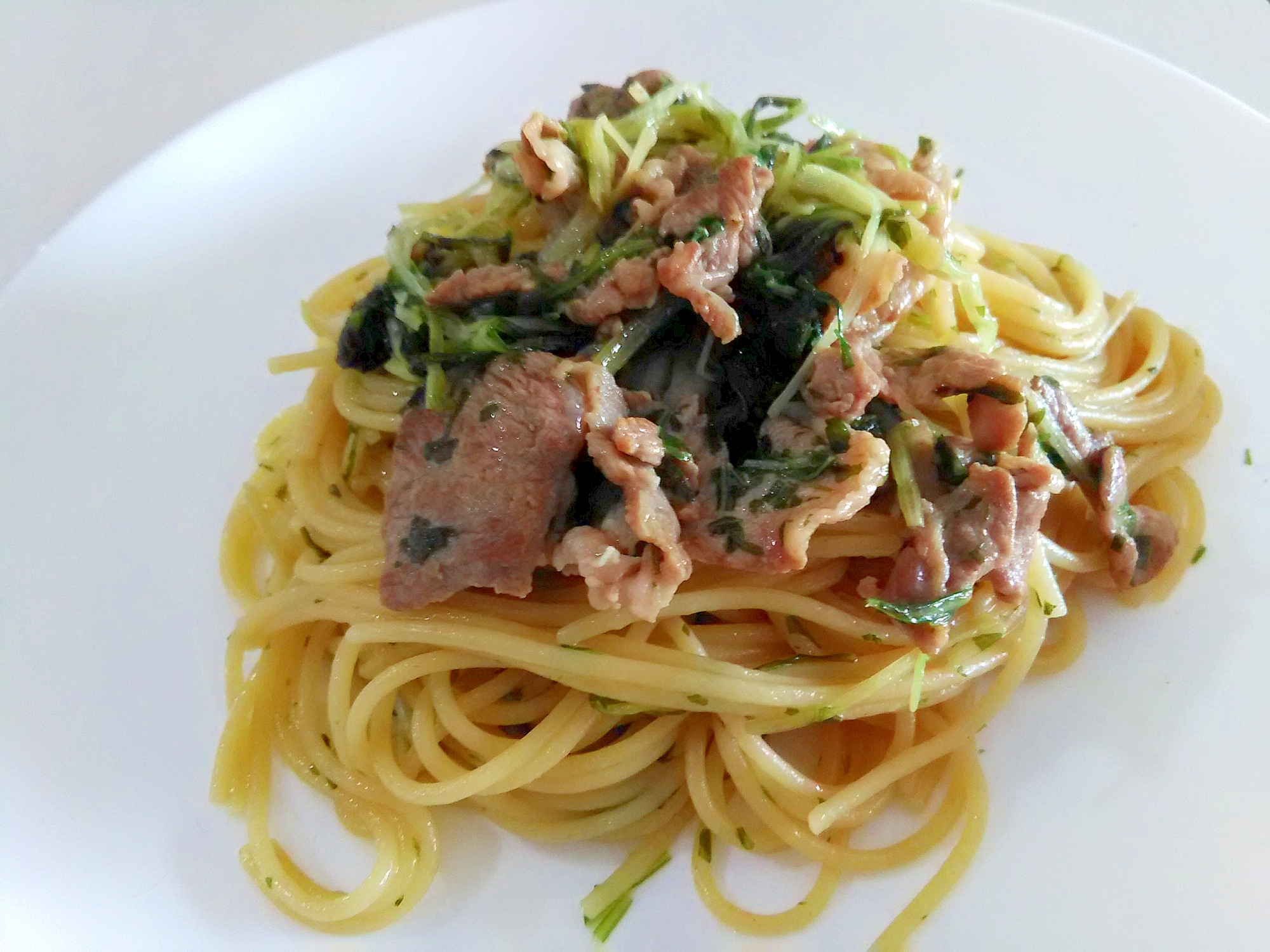 白い大皿に盛られた水菜と豚肉のバター醤油パスタ