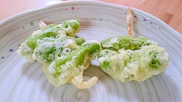 白っぽい和風の皿に盛られた、ふた串のししとうの天ぷら