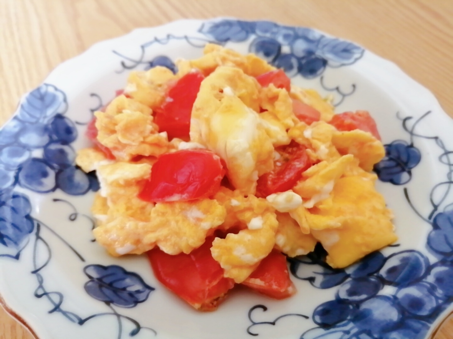 ぶどう模様の皿に盛りつけられたトマトとふんわり卵の中華炒め