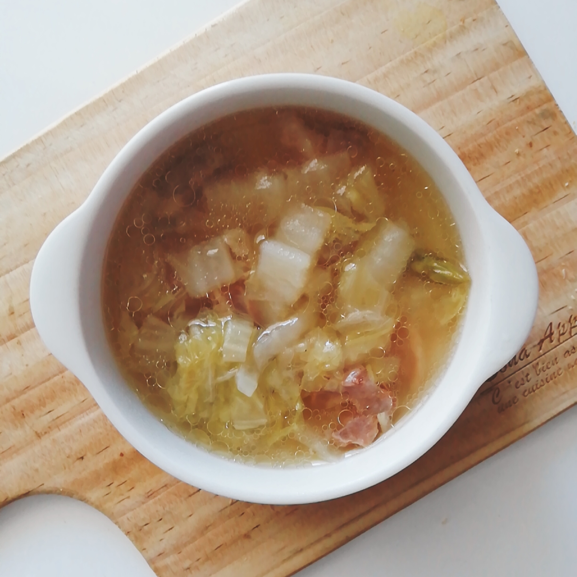 木製カッティングボード上の白いスープカップに盛られた、白菜と牛すじの中華風スープ