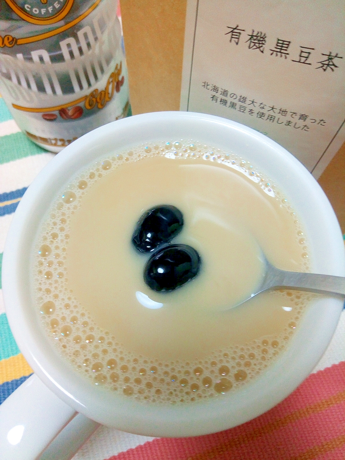 白いカップに入った黒豆茶ときな粉のカフェオレに黒豆がトッピングされている