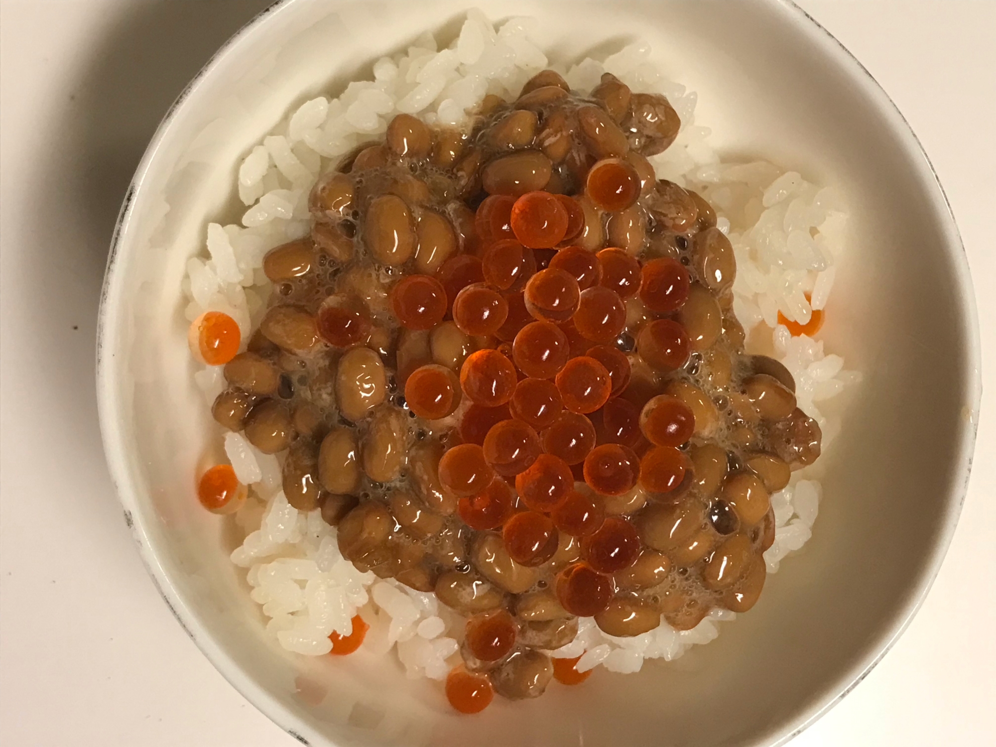 白いお茶碗に盛り付けられているいくら納豆ごはん