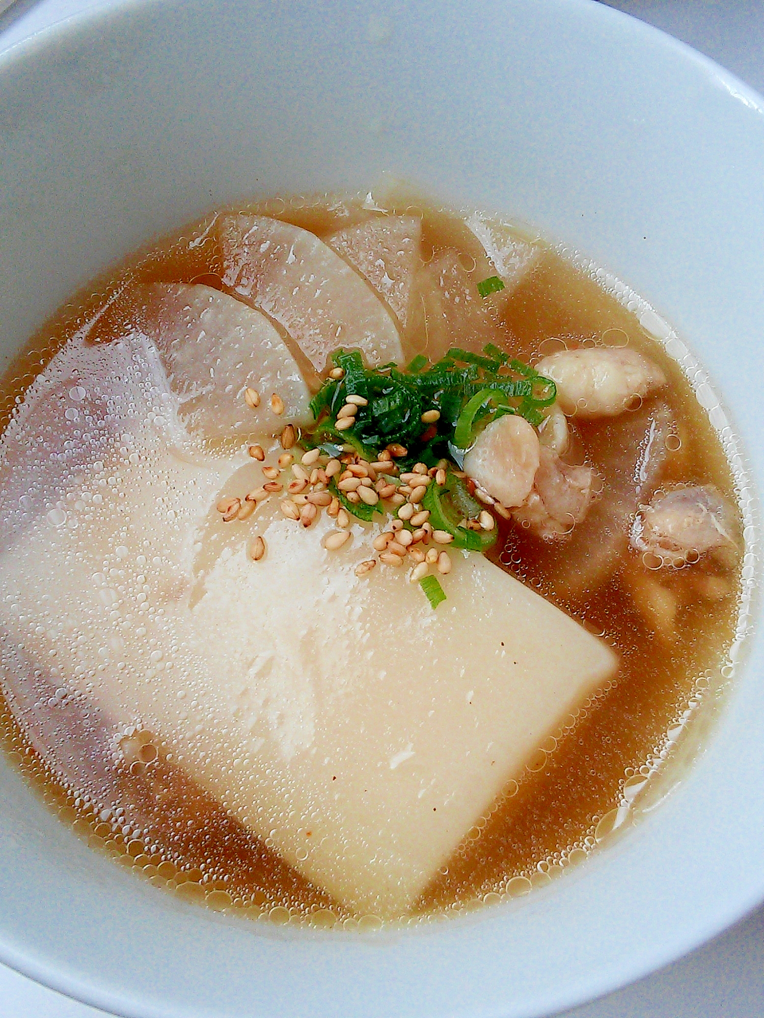 白いスープ皿に鶏ももと大根のあっさり中華雑煮が盛られている