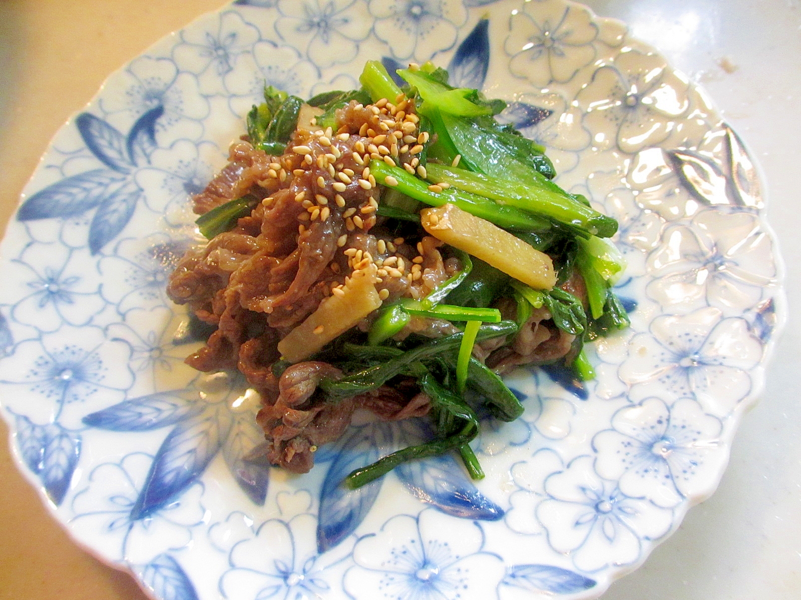 青い柄が入った皿に盛り付けた壬生菜の肉炒め