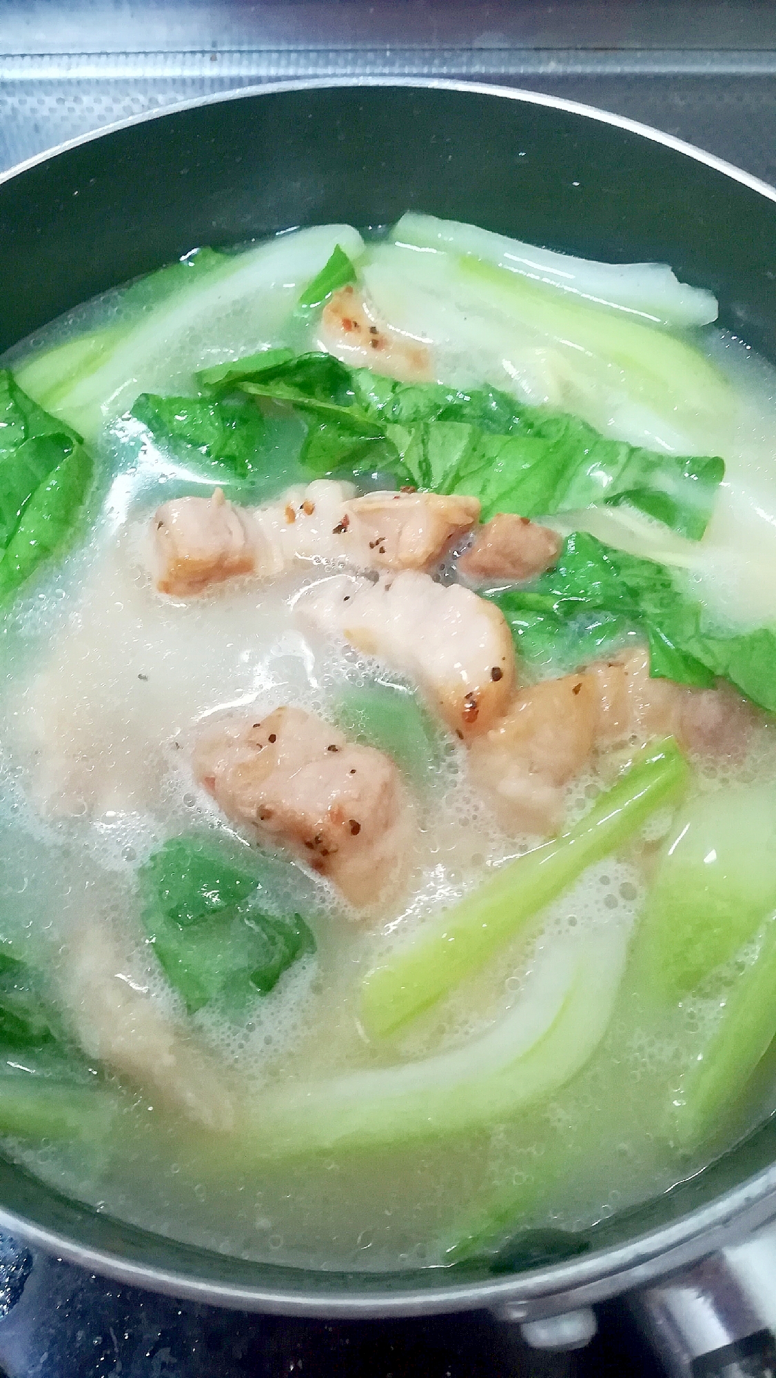 鍋でチンゲン菜と豚肉の白湯スープを作っている様子