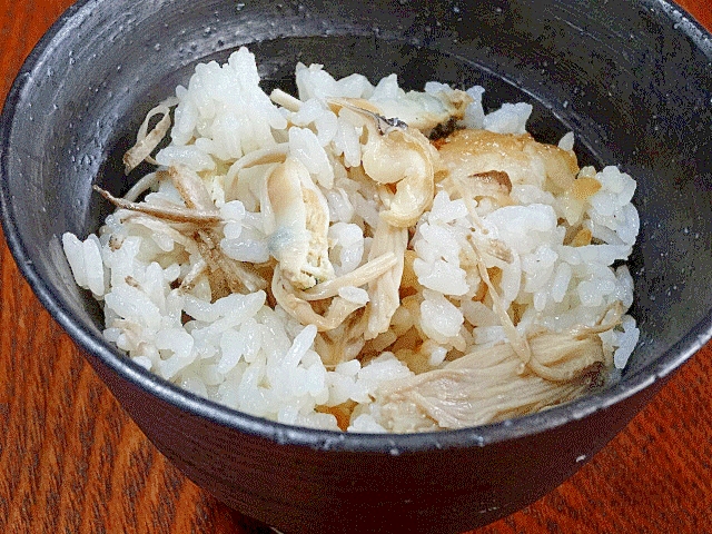 黒い陶器の茶碗に盛られた、はまぐりの炊き込みご飯