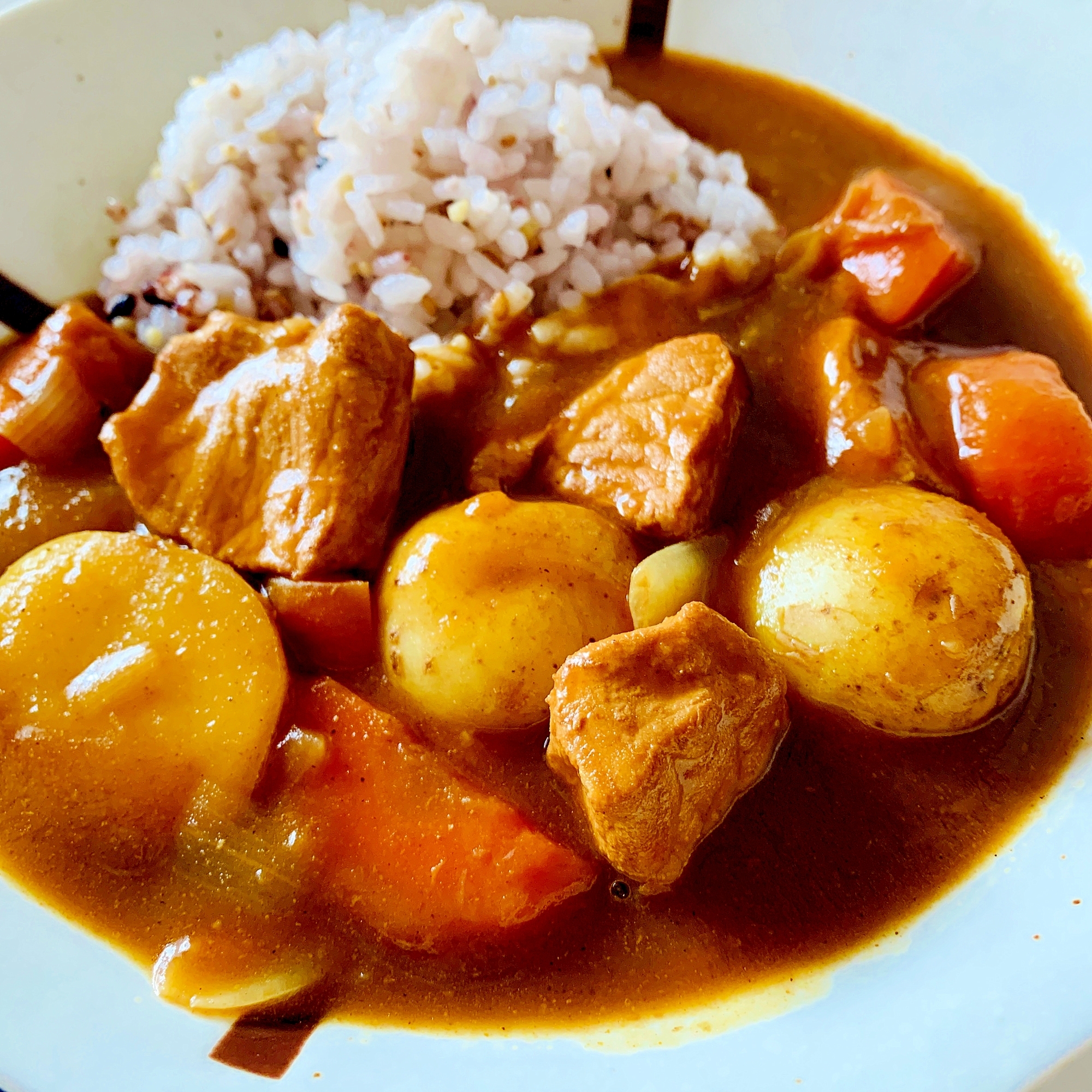 白色の皿に盛られた小さいじゃがいものまるごとカレー