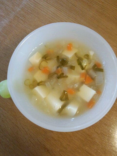 白いスープカップに豆腐と野菜がたくさん入った味噌汁が入っている