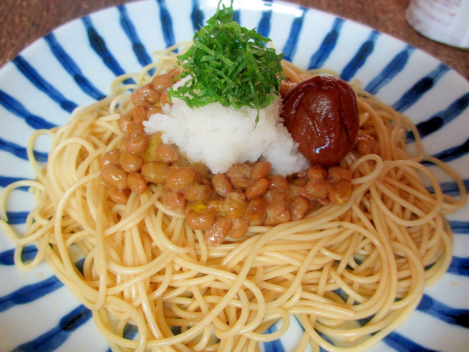 青いラインが入った皿に盛られたおろし納豆スパゲッティ