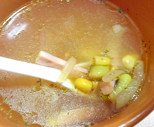 茶色い茶碗に盛られたベーコンと枝豆とコーンのコンソメスープ