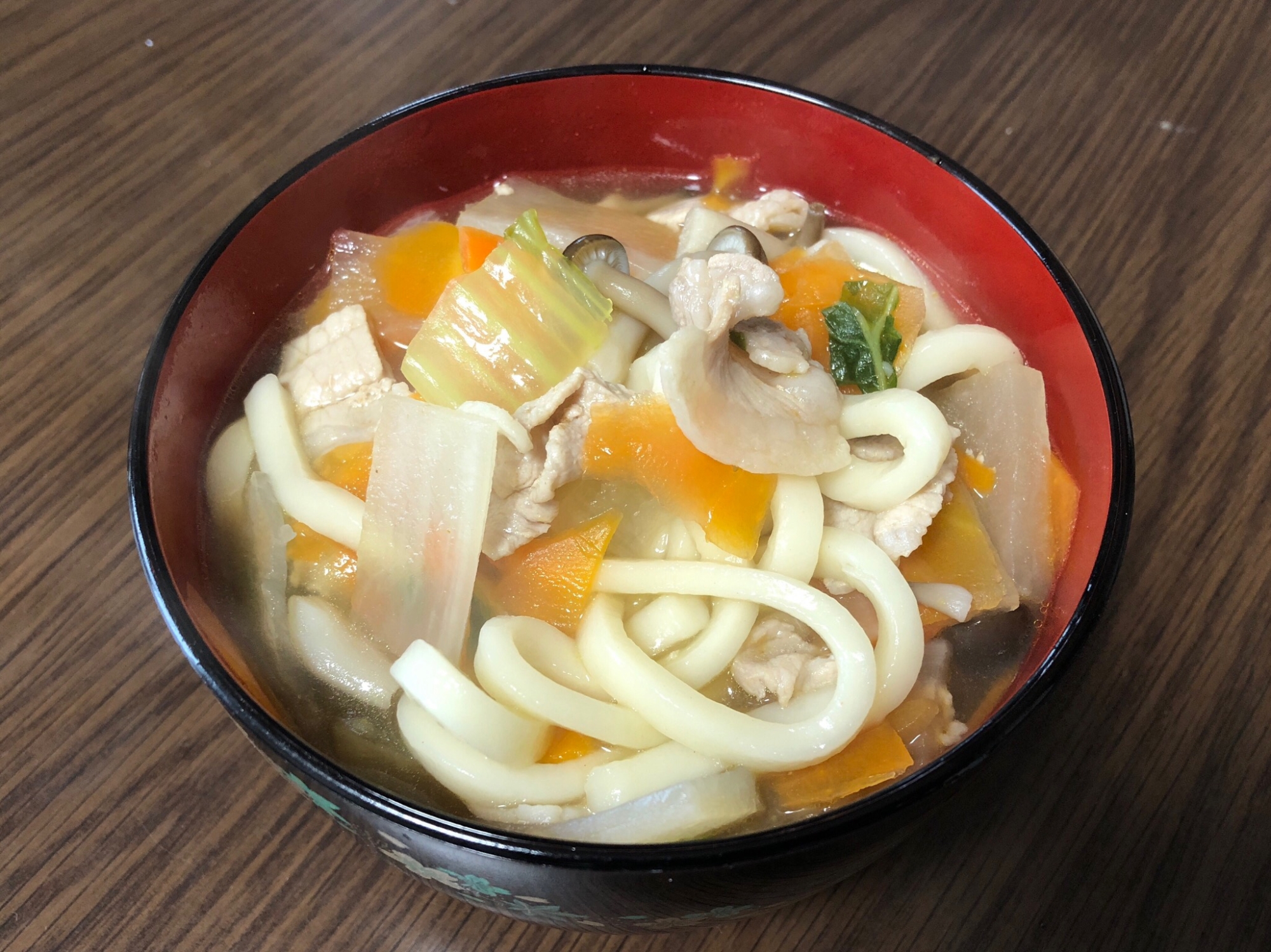 漆の器に盛られている豚肉と野菜のあんかけうどん