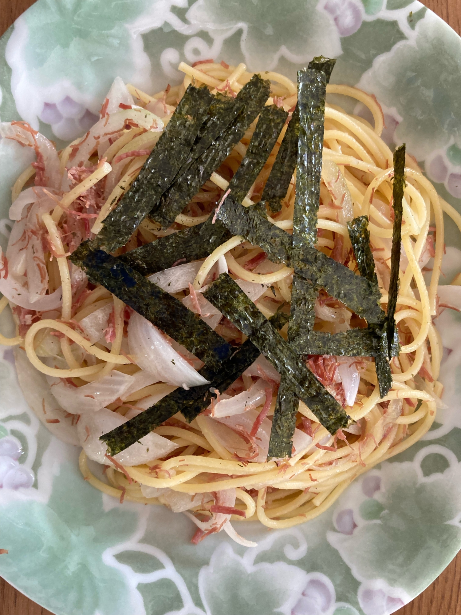 和風に仕上げたコンビーフと玉ねぎのパスタが海苔を添えてみどり色の器に盛り付けられているところ