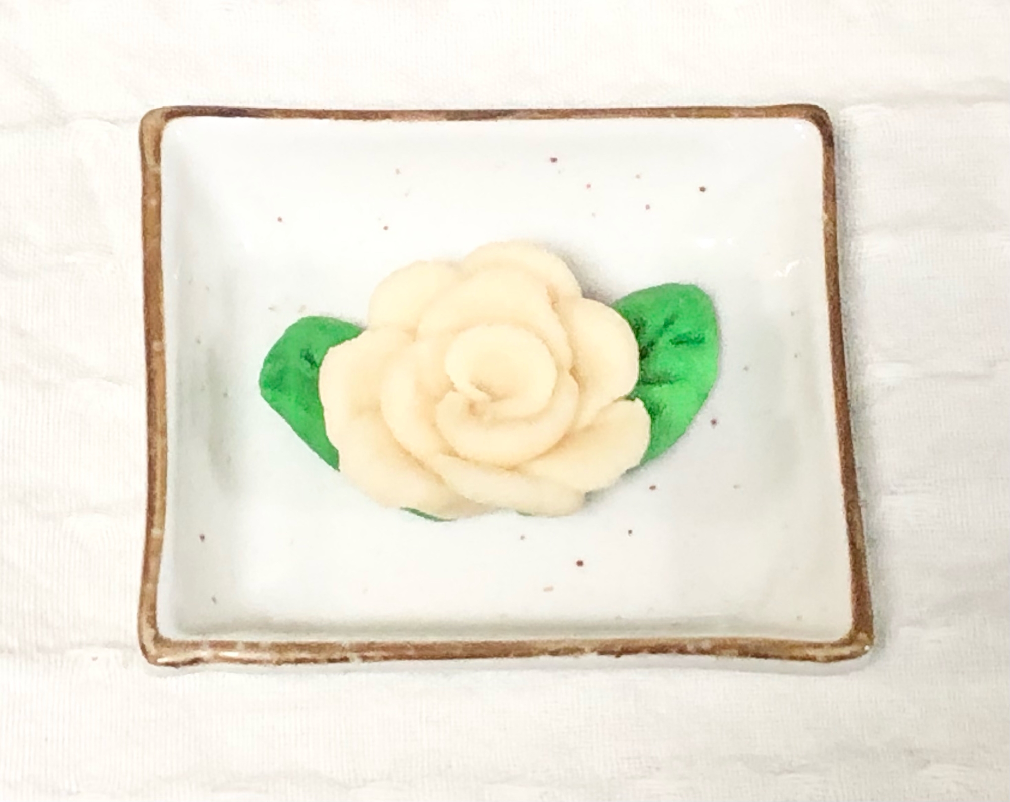 四角い皿に盛られた、葉付きの白バラ