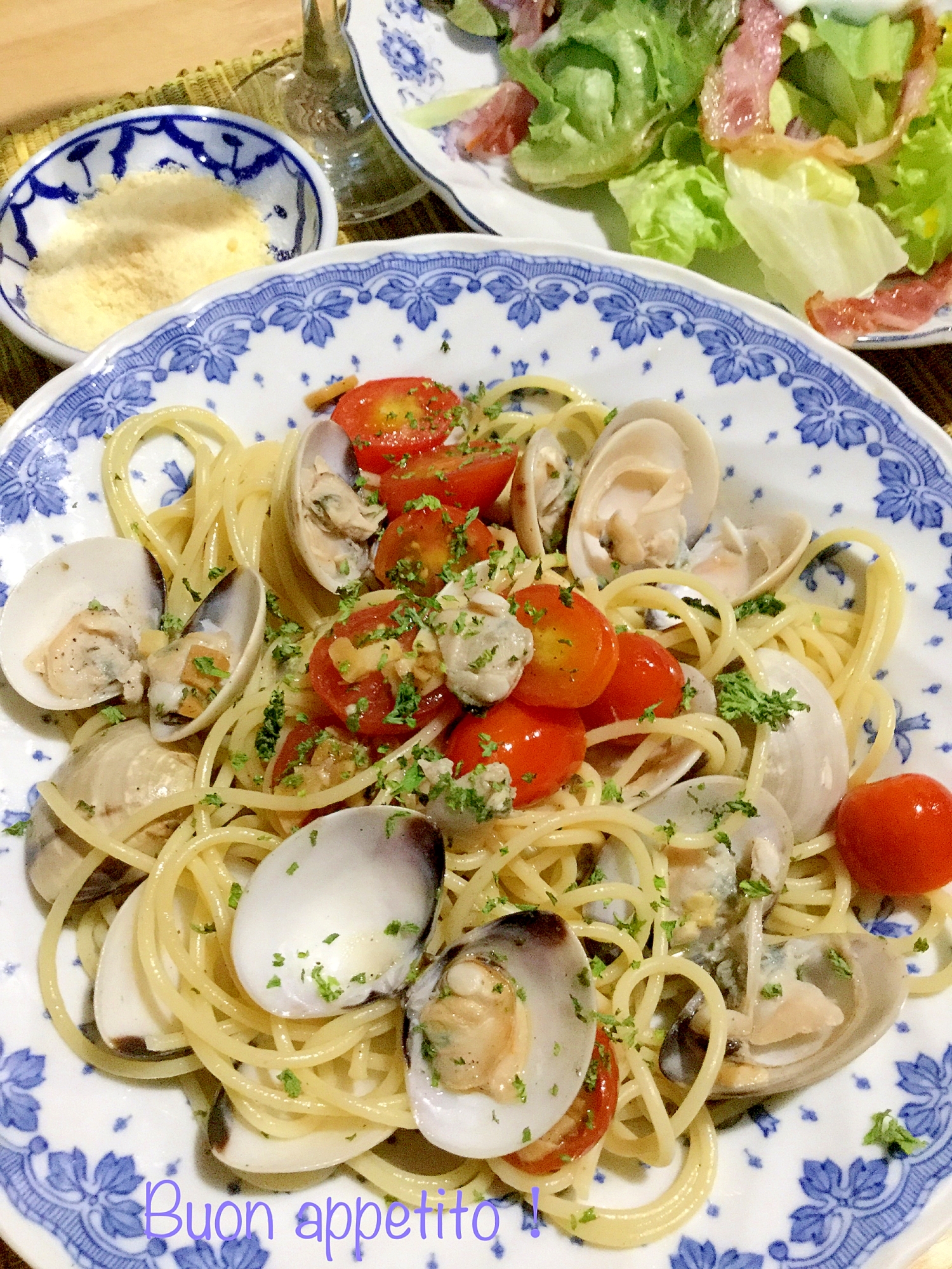 青い柄の皿に盛られたはまぐりとミニトマトのパスタ