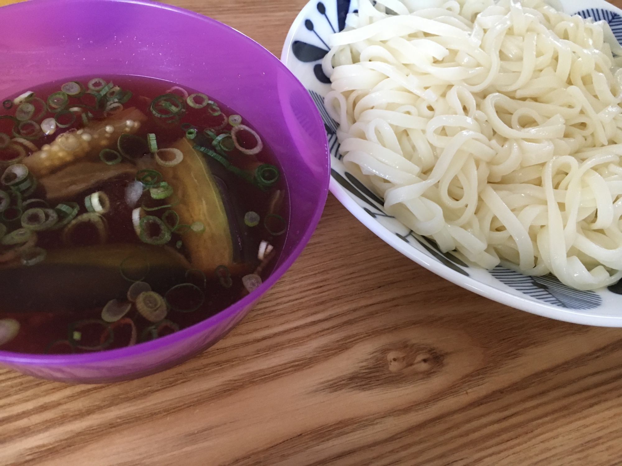 皿に盛りつけたざるうどんと、焼きなす入りのつけ汁が入った紫色の器