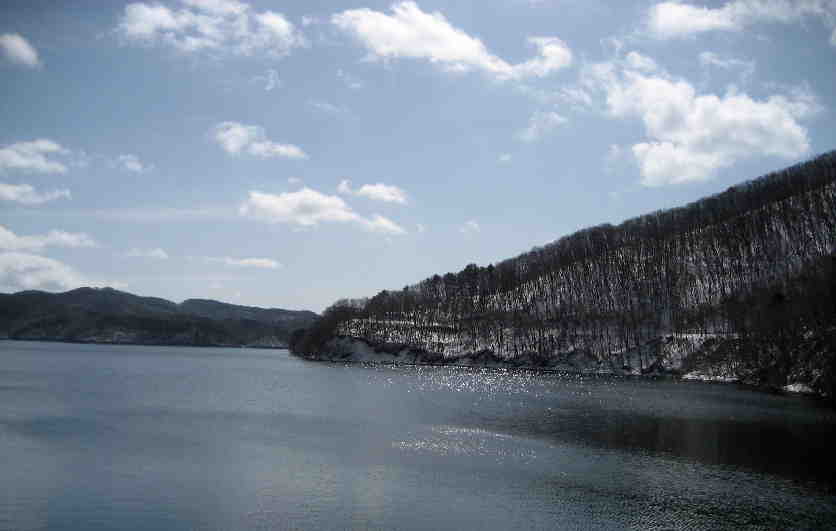 右側の山の向こうは真っ白なのに　放水側の湖面は春のような顔です